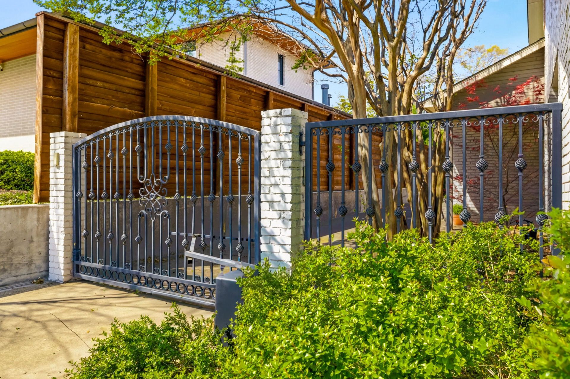 Wrought-iron driveway gate with masonry columns by Park Cities Fence in Highland Park, TX