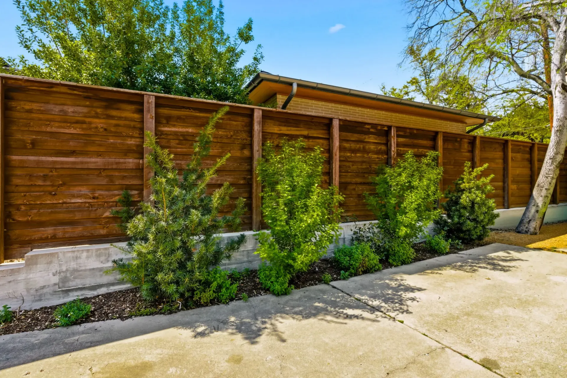 Stained horizontal wood privacy fence with landscaping in University Park, TX